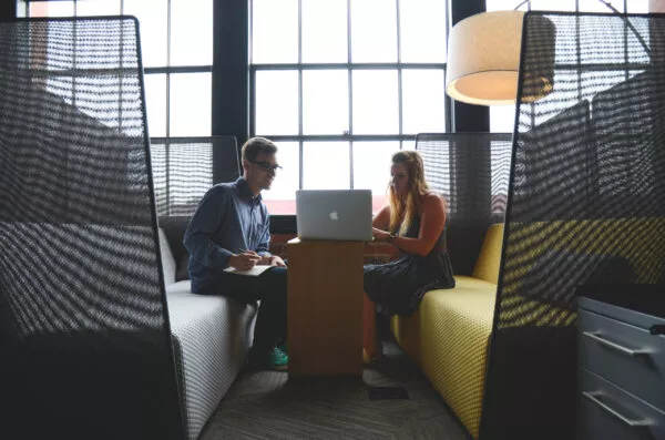Canva Smiling Man and Woman Both Sitting on Sofa Both Looking at Silver Macbook scaled e1588261859240.jpg