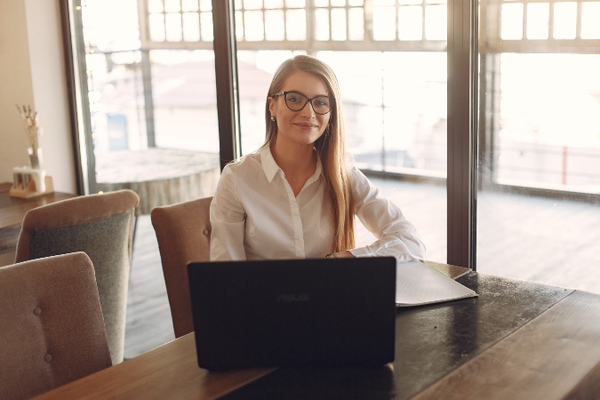 Canva Woman in White Polo Shirt Sitting In Front Of A Black Laptop